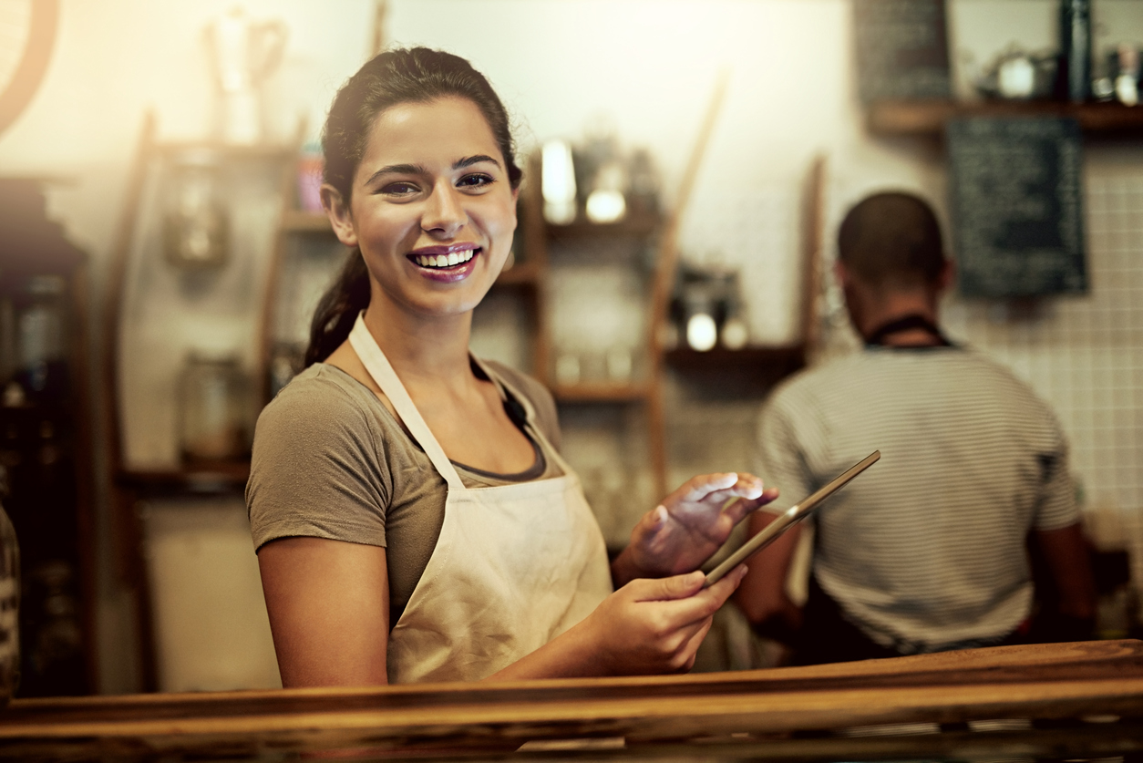 Young woman using a digital tablet with local NYC merchant services while working in a coffee shop