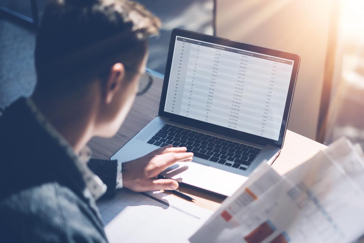 closeup of businessman working on financial spreadsheet on laptop rearview